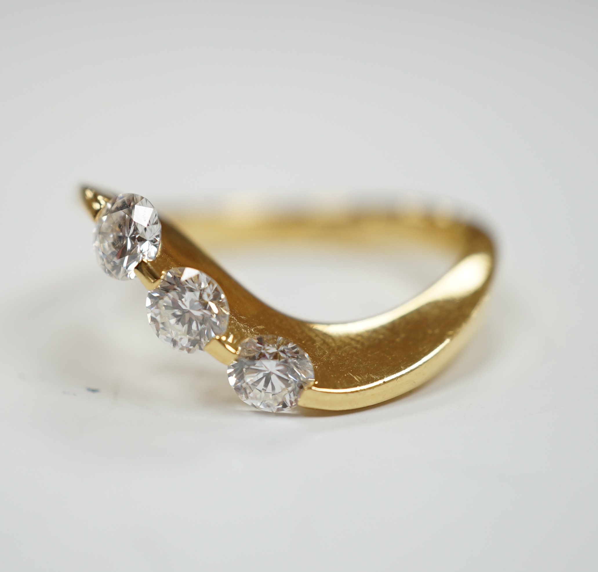 A modern 750 yellow metal and three stone diamond set crossover ring, size P, gross weight 5.4 grams.